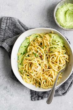 a white bowl filled with pasta and guacamole on top of a table