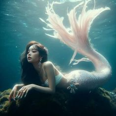 a woman with long hair sitting on top of a rock under water