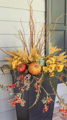 a planter filled with fall flowers and pumpkins