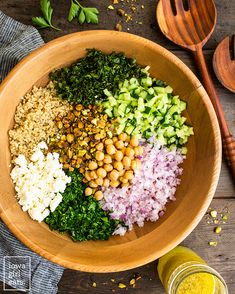 a wooden bowl filled with different types of food next to spoons and measuring cups