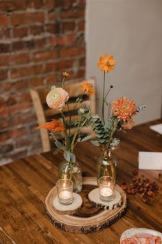 two vases filled with flowers sitting on top of a wooden table