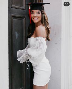 a woman wearing a graduation cap and gown posing for a photo in front of a door