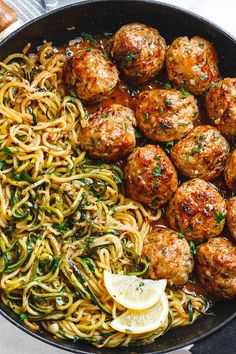 spaghetti and meatballs in a skillet with lemon wedges on the side, ready to be eaten