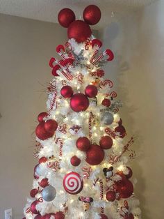 a white christmas tree decorated with red and silver ornaments, candy canes and balls