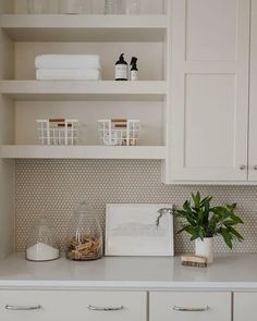 a kitchen with white cabinets and shelves filled with items