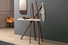 a coat rack and mirror on a wall in a room with grey walls, wood flooring and furniture