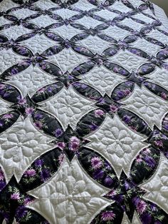 a quilted bedspread with purple and black flowers on the edges is shown