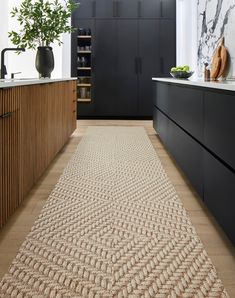 an area rug in the middle of a kitchen with black cabinets and counter tops on both sides