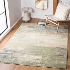 a living room area with a chair, mirror and large rug on the hardwood floor