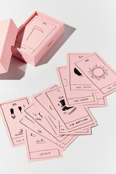 a pink box with six cards in it on a white surface next to the card game