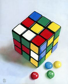 a rubik cube and three balls on a white surface