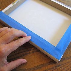 a person is holding a piece of paper in front of a box that has been cut out