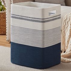 a blue and white basket sitting on top of a carpeted floor next to a couch