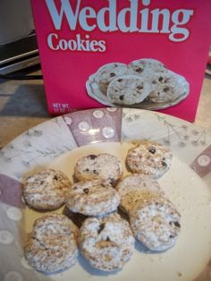 a white plate topped with cookies next to a pink wedding card and box of cookies