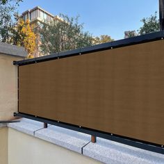 a large brown screen on the side of a building with trees and buildings in the background