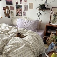 an unmade bed in a bedroom with pictures on the wall above it and coffee cup