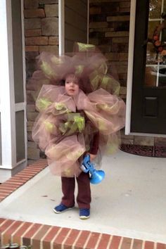 a young child wearing a costume made out of tulle and plastic gloves on the front porch