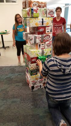 two children are playing with boxes in the middle of an office building while others look on