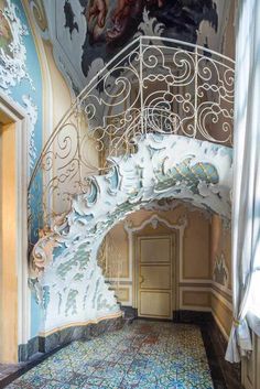 an ornate stair case in a room with paintings on the walls and ceiling above it