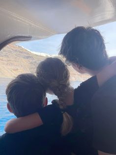 two children with braids on their heads looking out the window at mountains and water