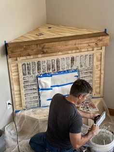 a man is sitting on the floor working on some construction material in front of a fireplace