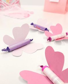 pink and white paper butterflies with crayons in the middle on a table top