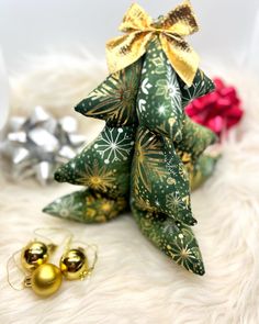 a small green christmas tree sitting next to two gold ornaments on top of a white furnishing