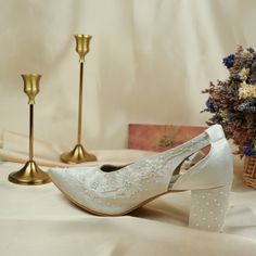 a pair of white shoes sitting on top of a table next to a vase with flowers