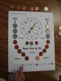 a person holding up a piece of paper with numbers and coins around it on top of a wooden table