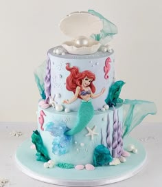 the little mermaid is sitting on top of this cake