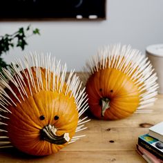 two orange pumpkins with spikes on them sitting on a wooden table next to books