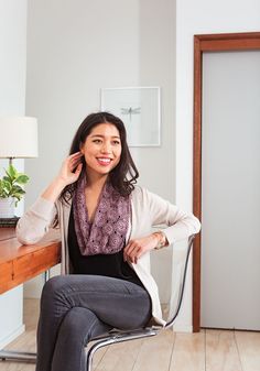 a woman sitting in a chair with her hand on her head and smiling at the camera