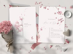 the wedding stationery is laid out on top of the table with pink flowers in vases