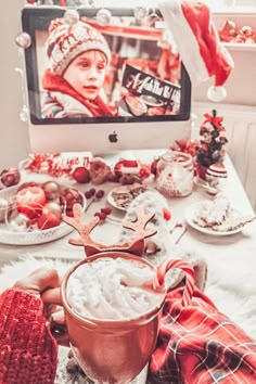 a person is holding a drink in front of a tv with christmas decorations on it