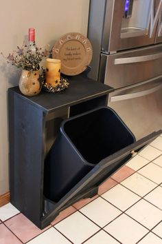 a black trash can sitting next to a refrigerator