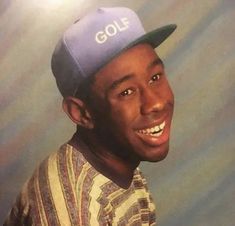 a man wearing a hat and smiling at the camera with his head tilted to the side