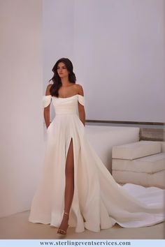 a woman in a white dress standing next to a wall with her leg up on the floor