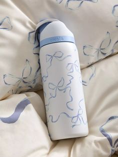 a white and blue water bottle sitting on top of a bed covered in sheets with butterfly designs