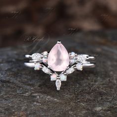 an image of a pink ring on top of a black stone surface with white stones