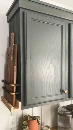 a kitchen with gray cabinets and wooden cutting board