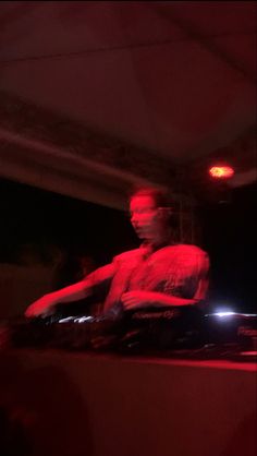 a man that is sitting down in front of a dj's turntables