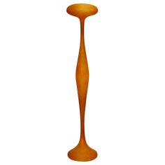 a tall orange vase sitting on top of a white floor next to a light fixture