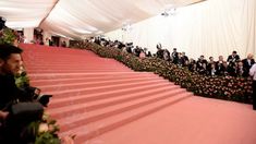 many people in suits and tuxedos are lined up on the red carpeted steps