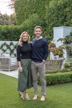 a man and woman standing next to each other in the grass