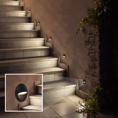 a set of stairs leading up to a wall with lights on it and an open door in the middle