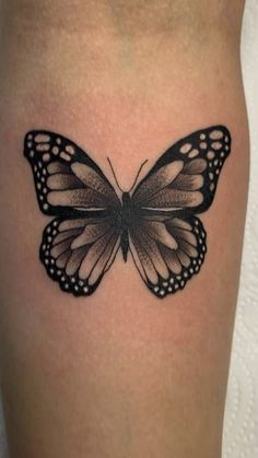 a black and white butterfly tattoo on the thigh