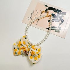 a white necklace with yellow flowers on it and a card attached to the neckline