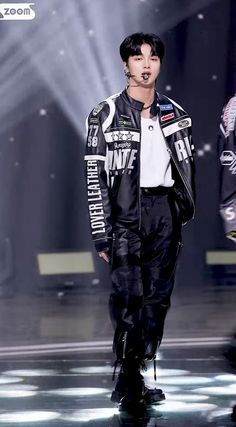 a man walking down a runway wearing black and white clothes with an embellishment on his face