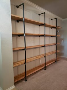 an empty room with some shelves and pipes on the wall in front of it, next to a carpeted floor