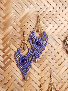 three pairs of beaded earrings sitting on top of a woven tablecloth next to other beads